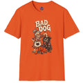 An orange short-sleeve crewneck t-shirt featuring a vintage-style graphic of a cartoon dog dressed in Halloween clothes next to a jack-o'-lantern, with the text 'BAD DOG' printed above.